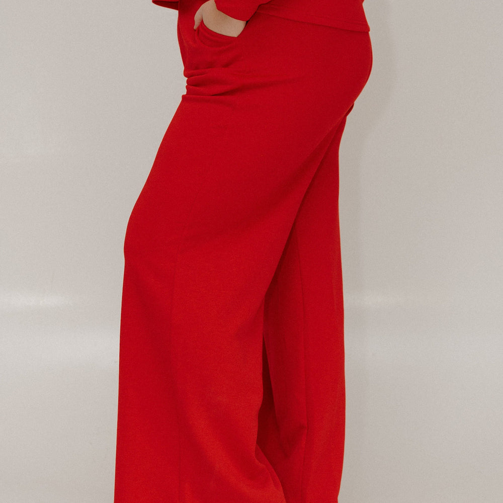 Person wearing a red outfit with wide-leg pants on a plain background