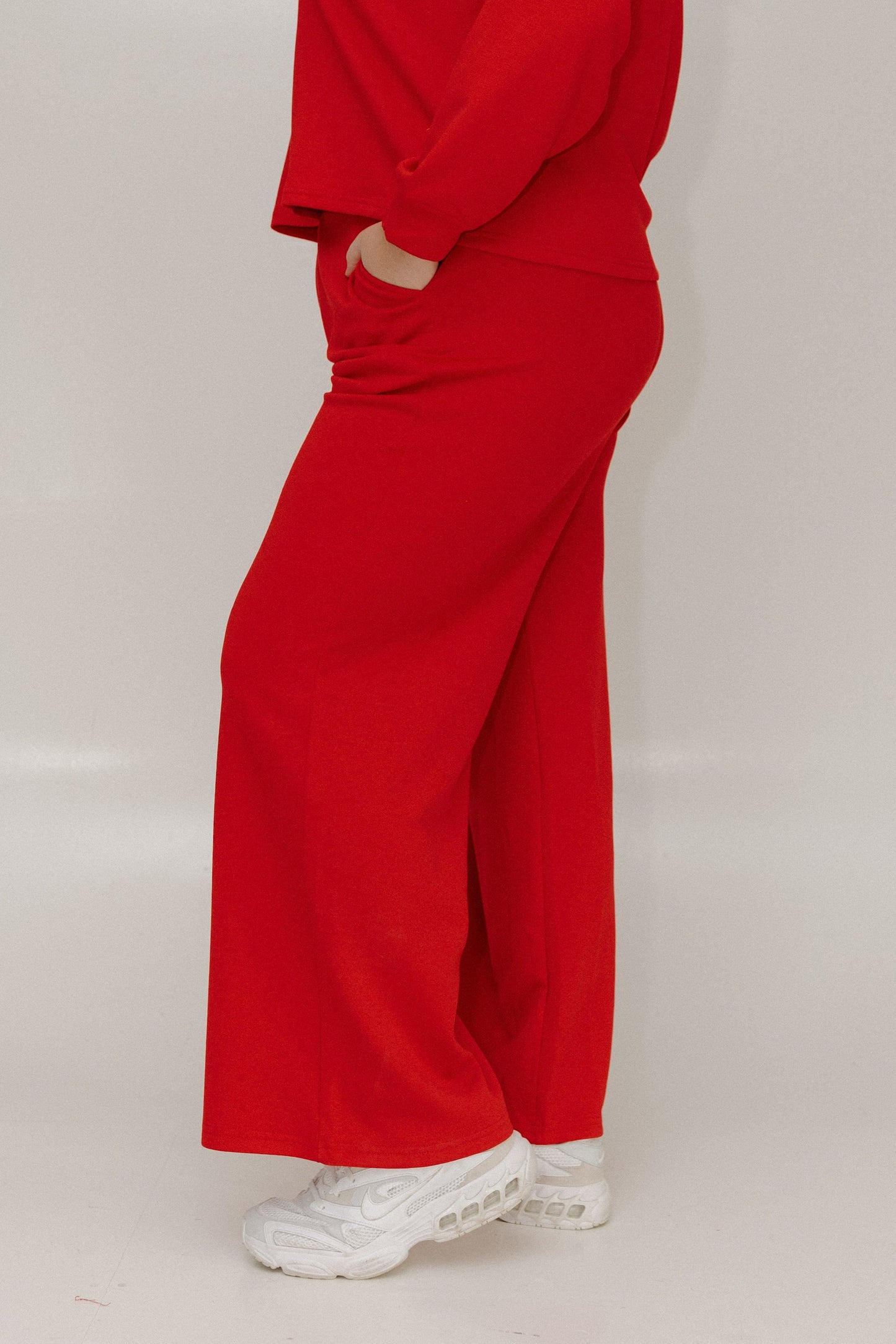 Person wearing a red outfit with wide-leg pants on a plain background