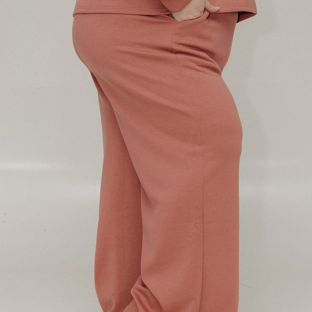 Person wearing a pink outfit with wide-leg pants on a plain background