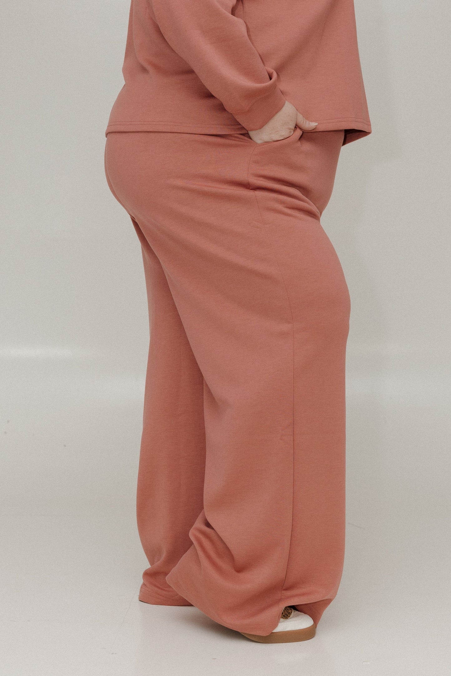 Person wearing a pink outfit with wide-leg pants on a plain background