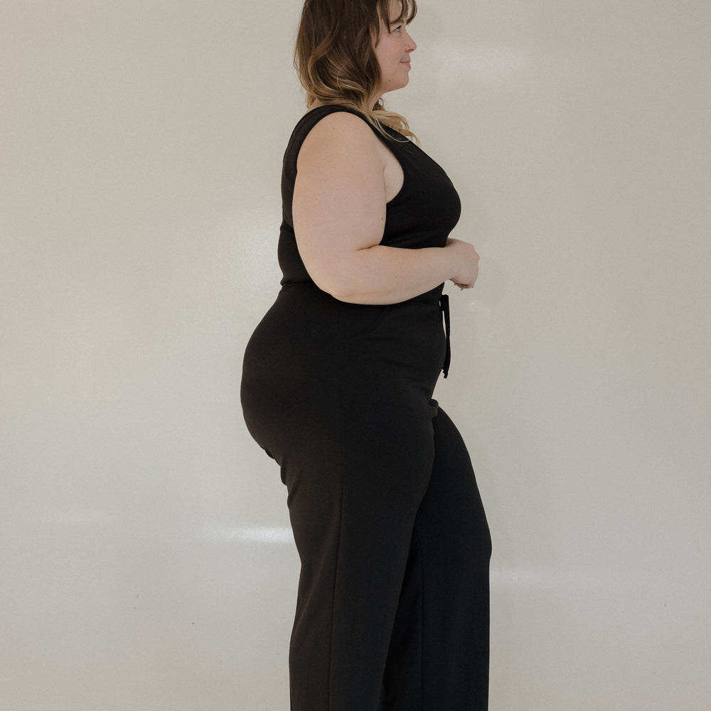 Person wearing a black outfit standing against a white background