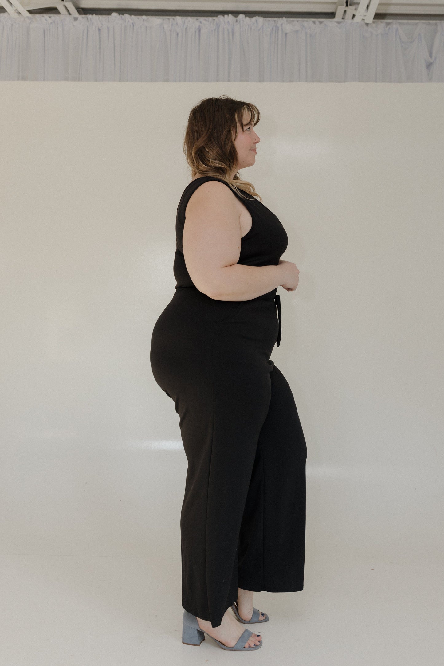 Person wearing a black outfit standing against a white background