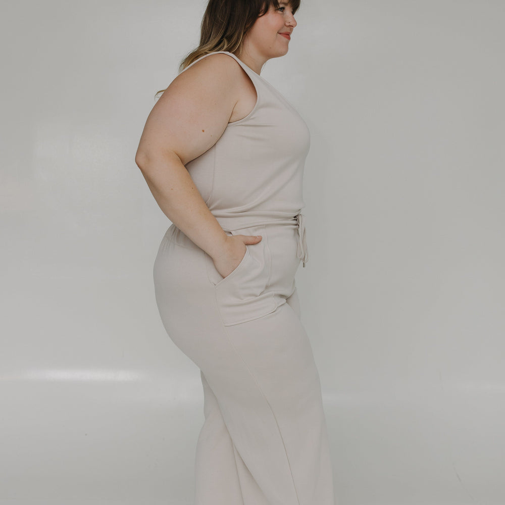 Woman wearing a light-colored dress standing against a white background