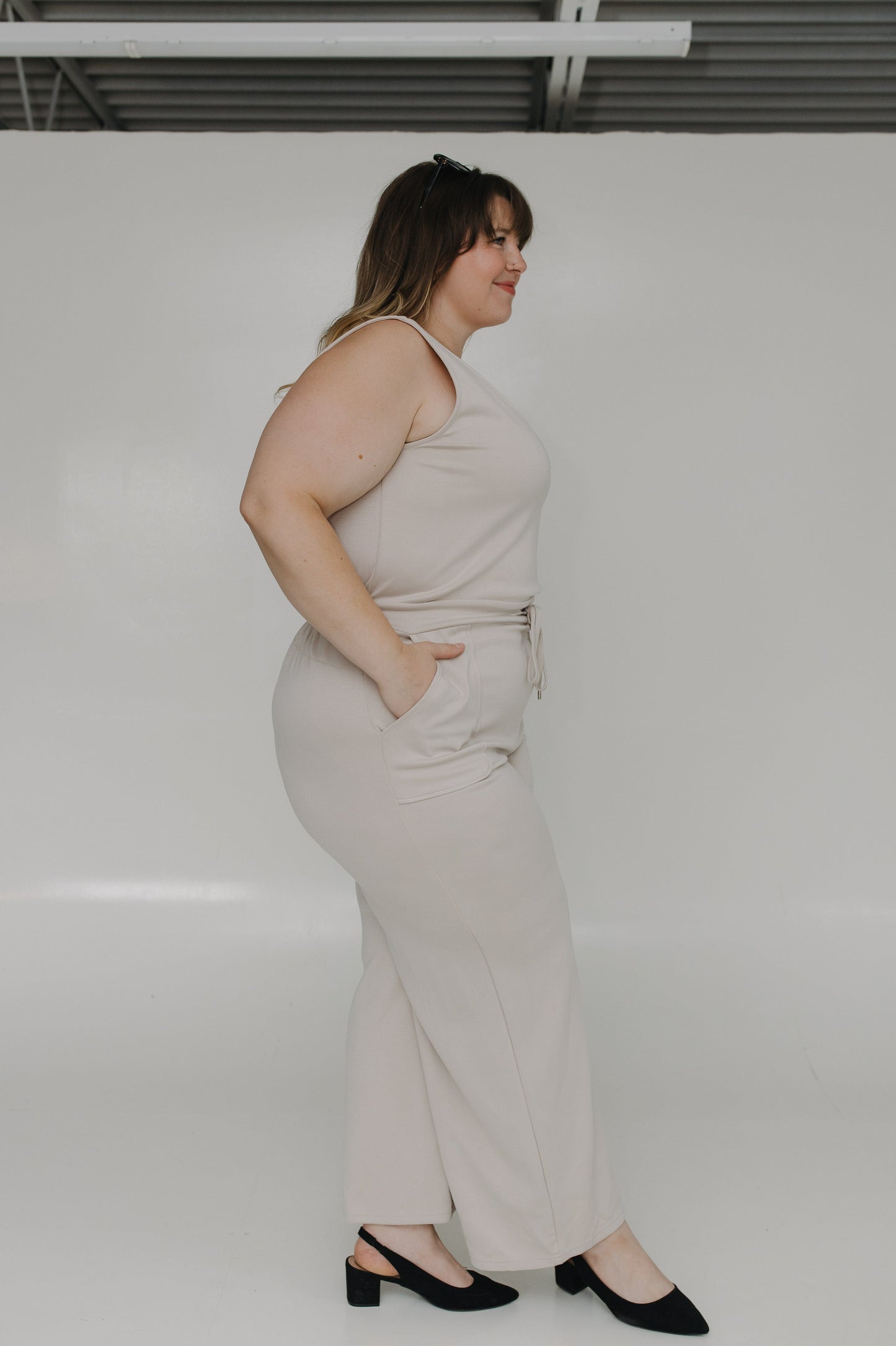 Woman wearing a light-colored dress standing against a white background