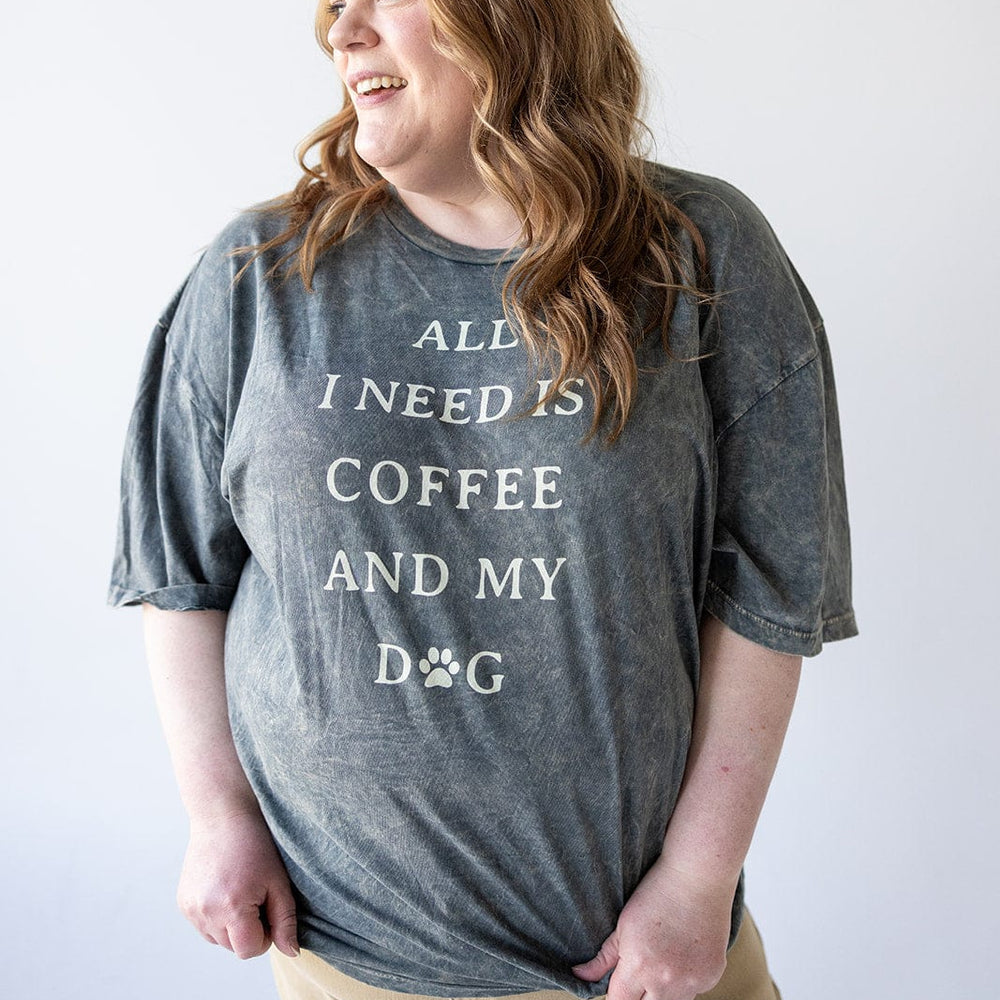 A person in a graphic tee that reads "ALL I NEED IS COFFEE AND MY DOG" is smiling and gazing to the side, perfectly embodying a casual outfit vibe.