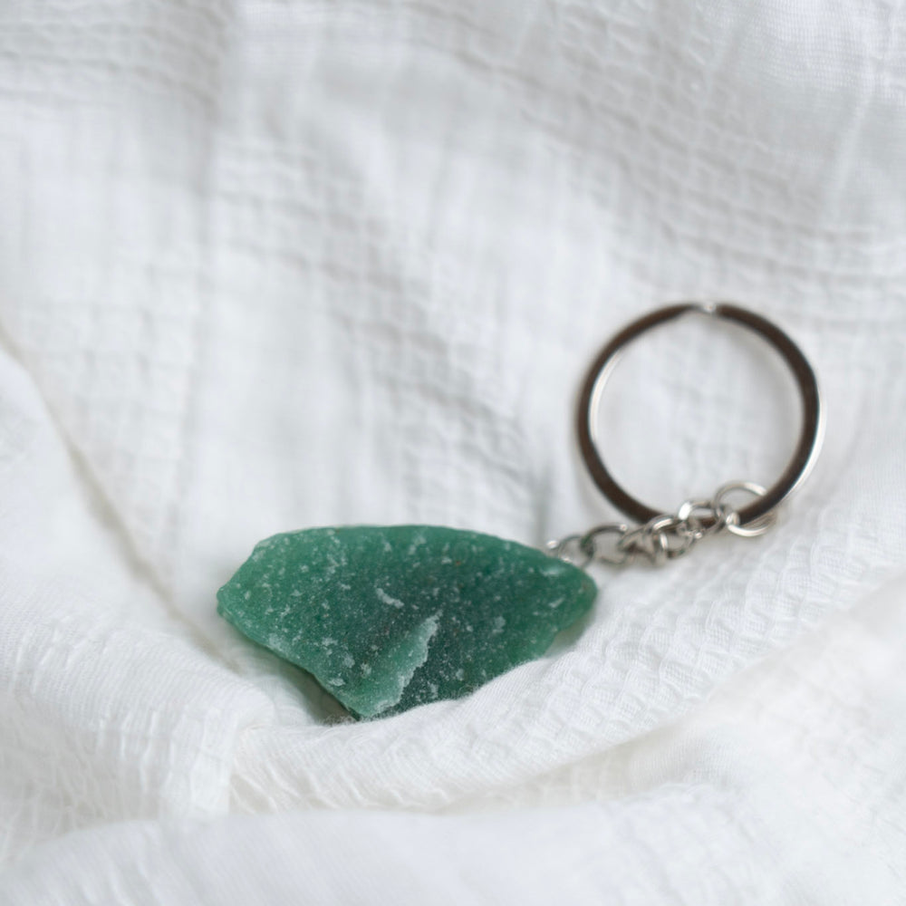 Green stone keychain on a white textured fabric background