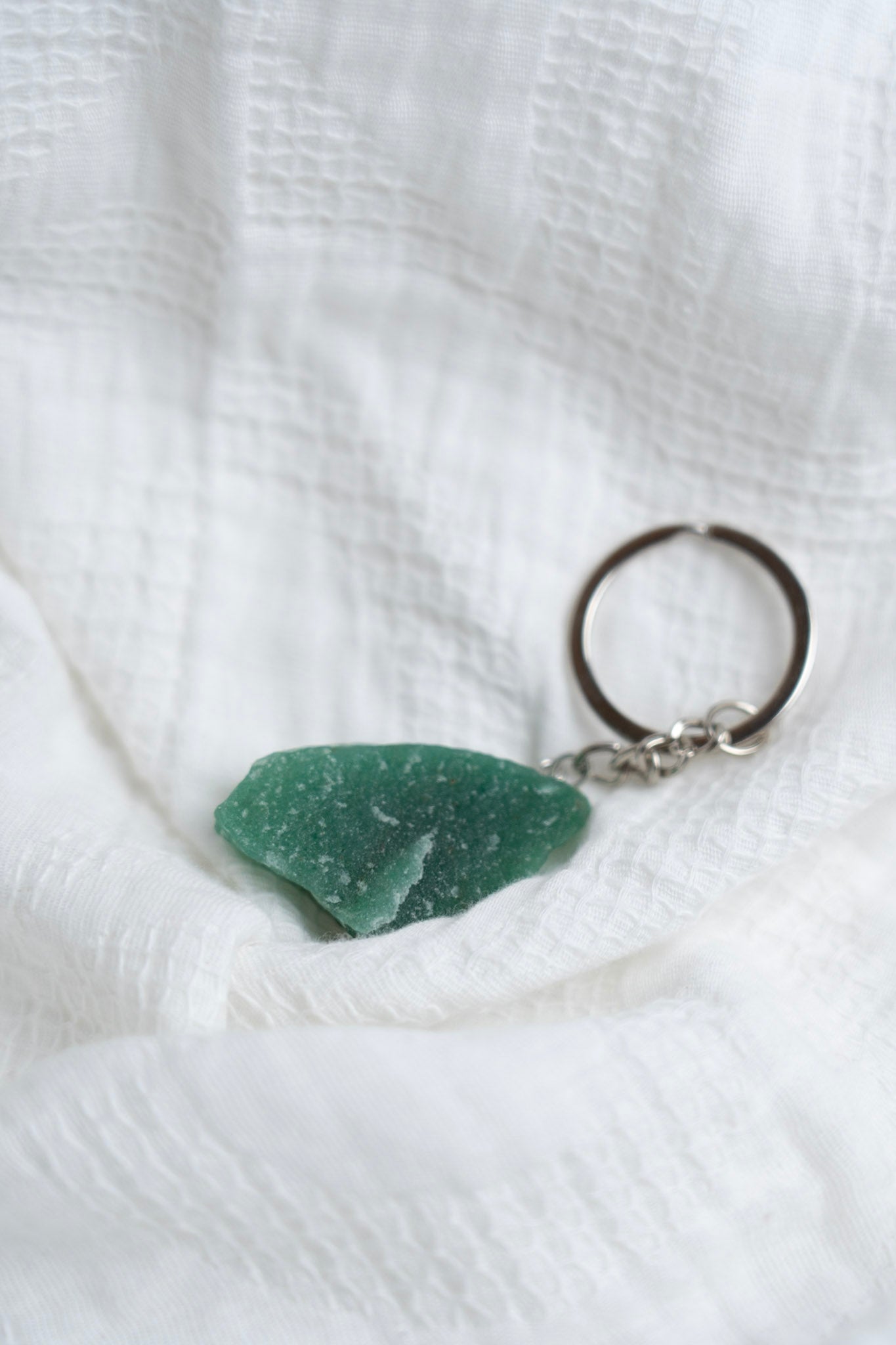 Green stone keychain on a white textured fabric background