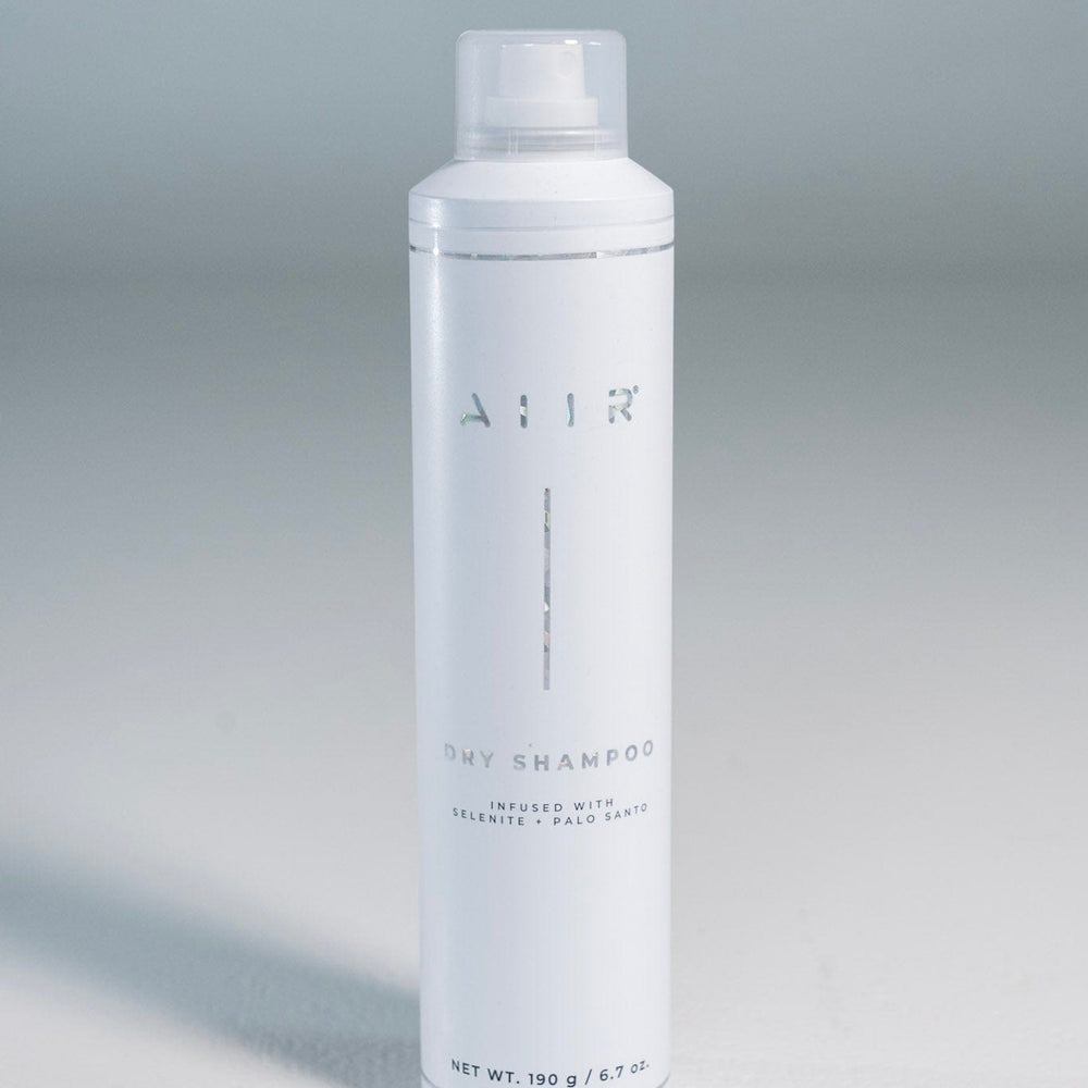 White dry shampoo bottle with AIIR branding on a gray background