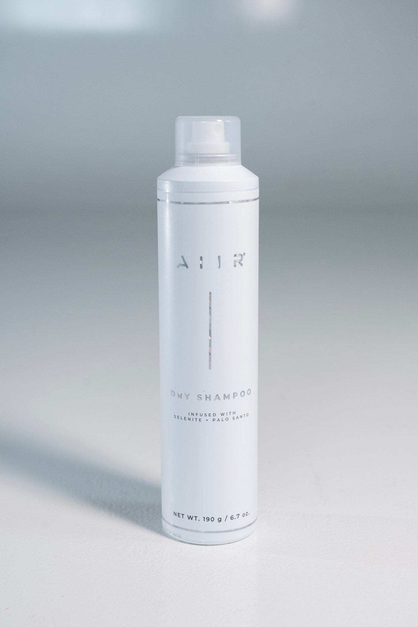 White dry shampoo bottle with AIIR branding on a gray background