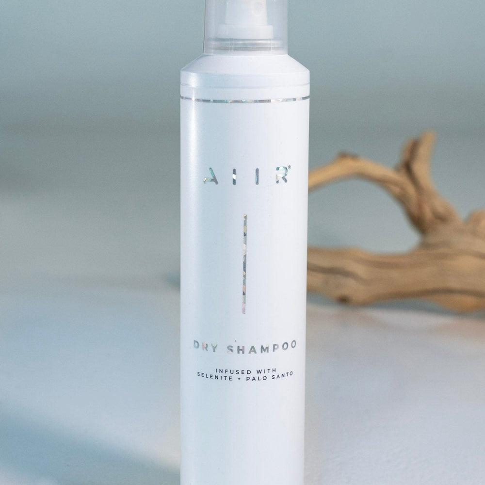 White bottle of AIIR dry shampoo on a light gray background