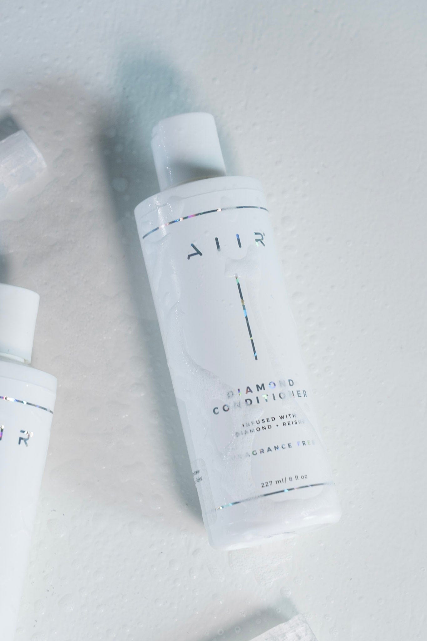 Two bottles of Allur diamond conditioner on a light gray background