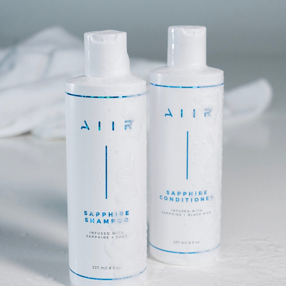 Two bottles of AHA shampoo and conditioner on a light gray background