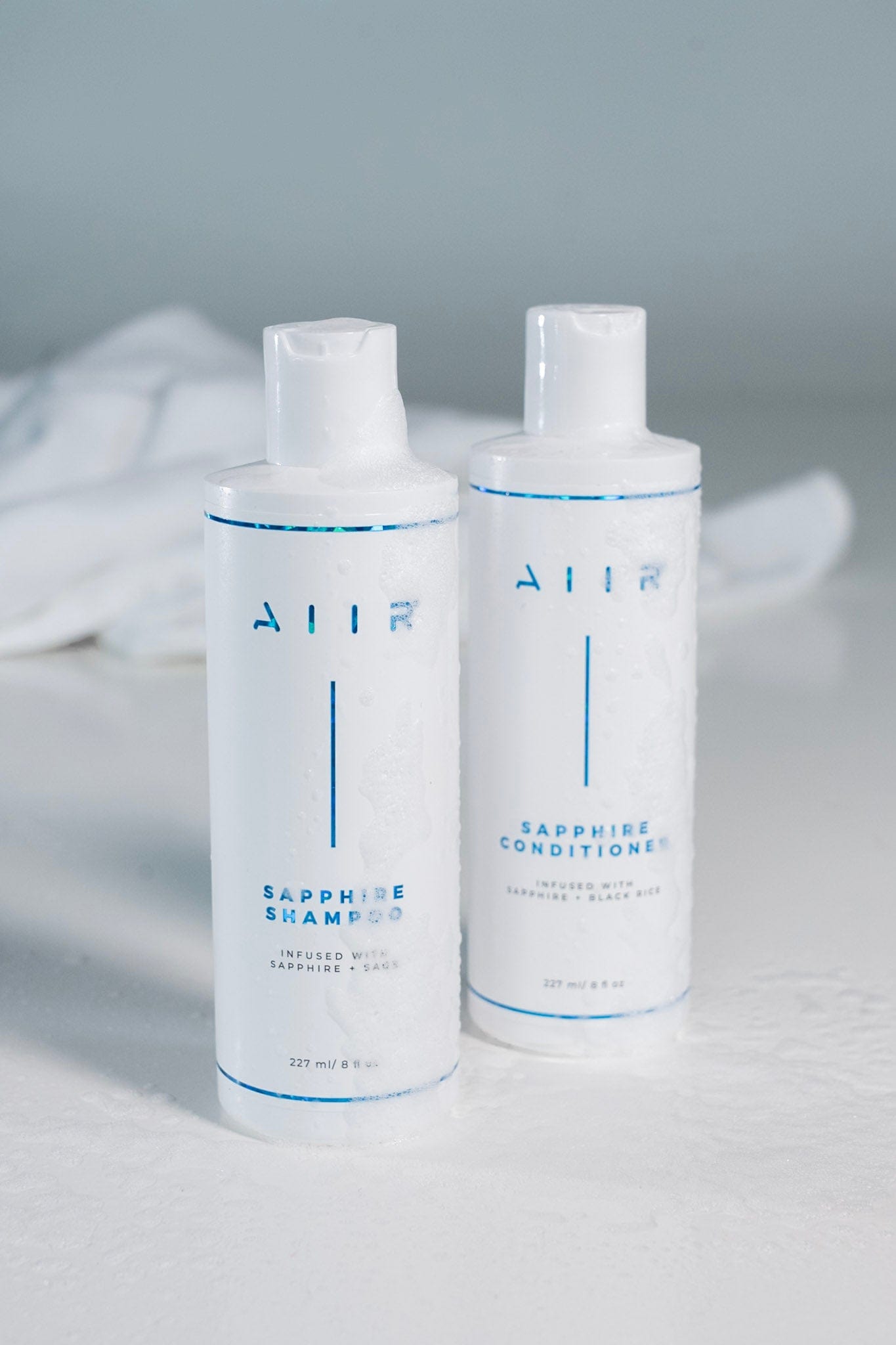 Two bottles of AHA shampoo and conditioner on a light gray background