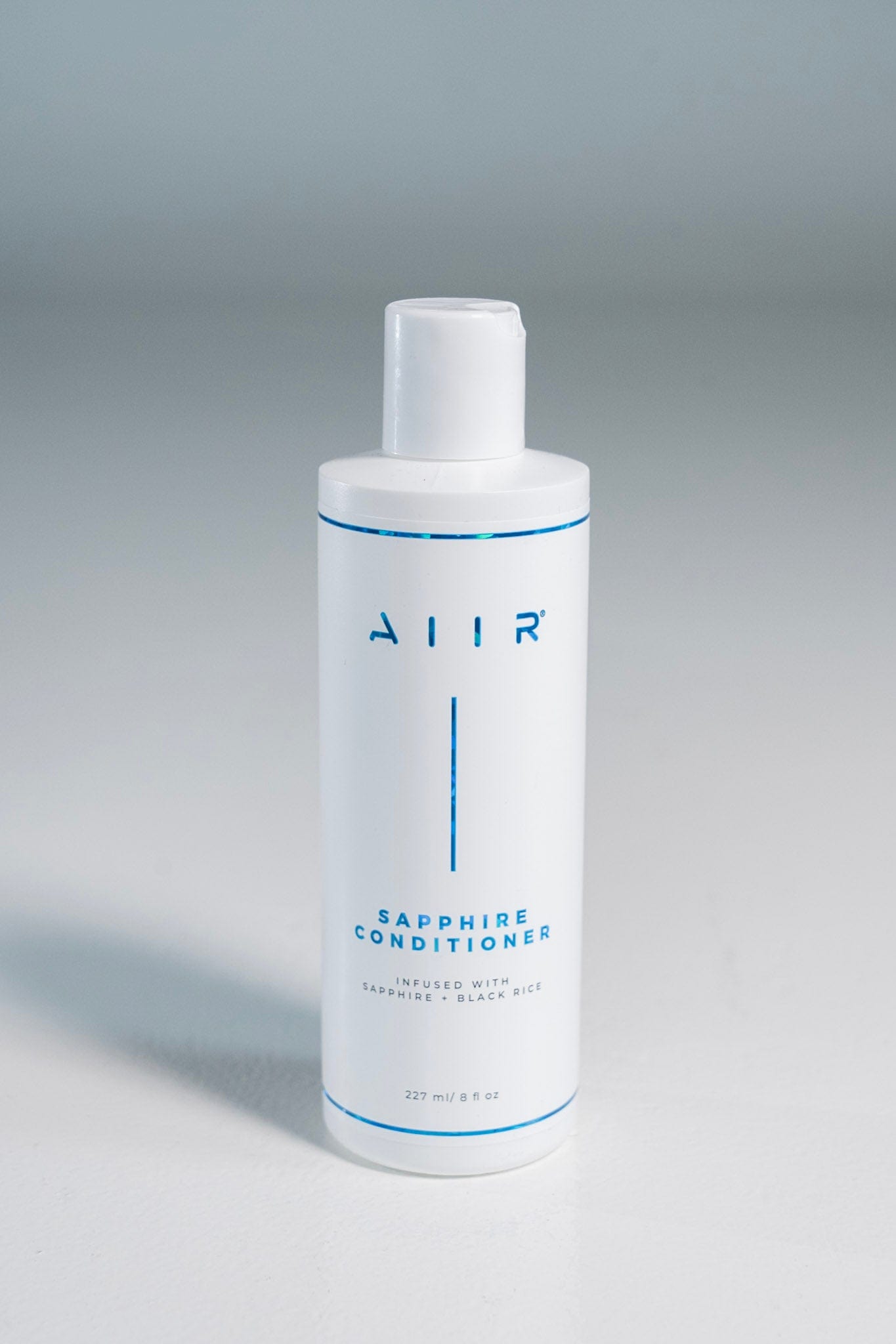 White bottle of AIIR Sapphire Conditioner on a gray background