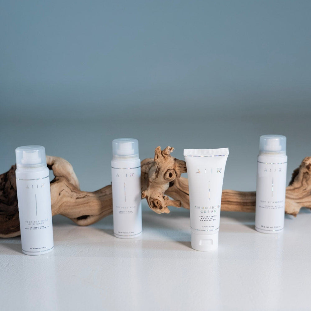 Four skincare bottles with labels on a light surface with driftwood.