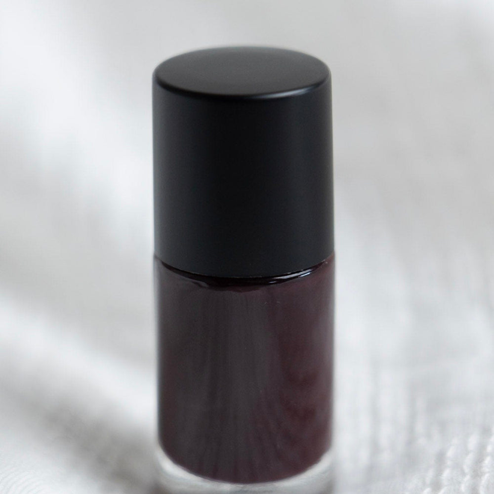 Balsamic water-based nail polish bottle on a white textured background textured white surface