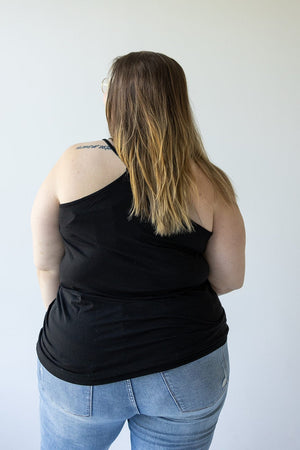 A person with long hair is standing with their back to the camera, dressed in a BASIC RACERBACK CAMI IN BLACK by Love Marlow and a pair of jeans.