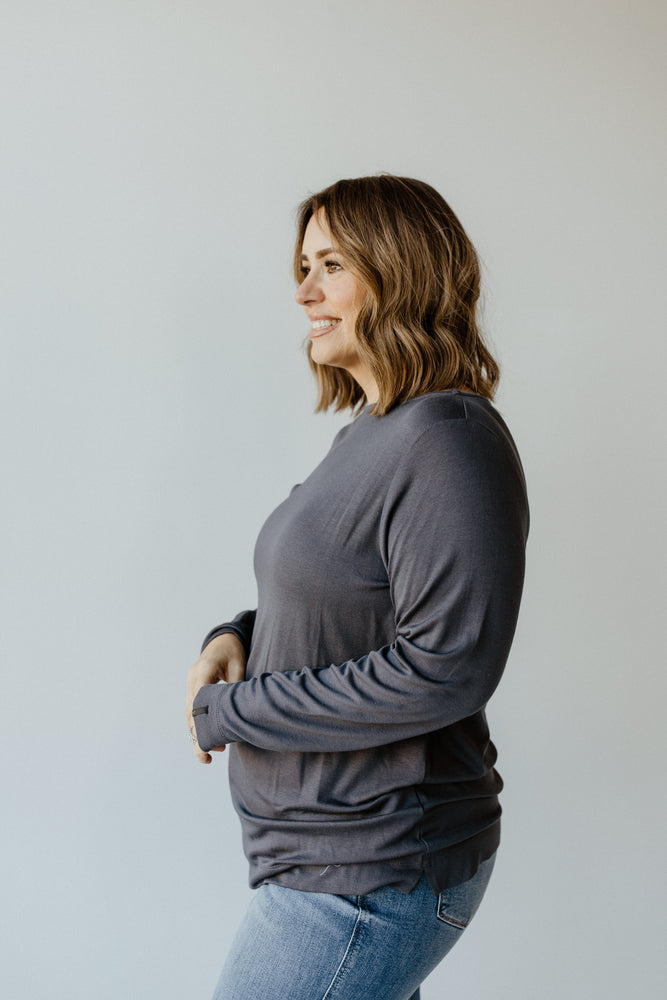 A person with wavy hair is wearing the Yesta Basic Long Sleeve Tunic Tee in Stargazing and a pair of jeans, standing with their back to the camera against a light gray background.