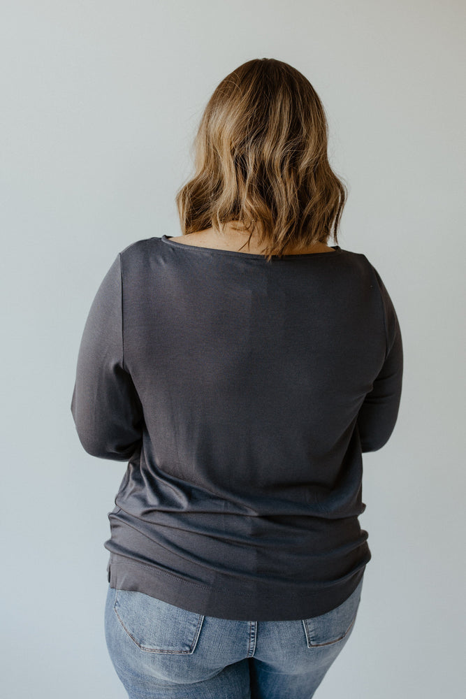 A person with wavy hair is wearing the Yesta Basic Long Sleeve Tunic Tee in Stargazing and a pair of jeans, standing with their back to the camera against a light gray background.