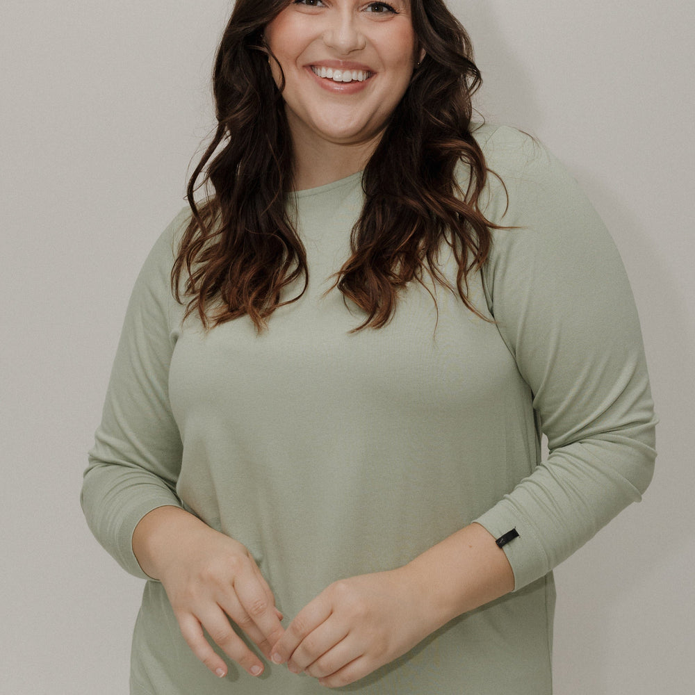 Woman wearing a light green long-sleeve top against a plain background