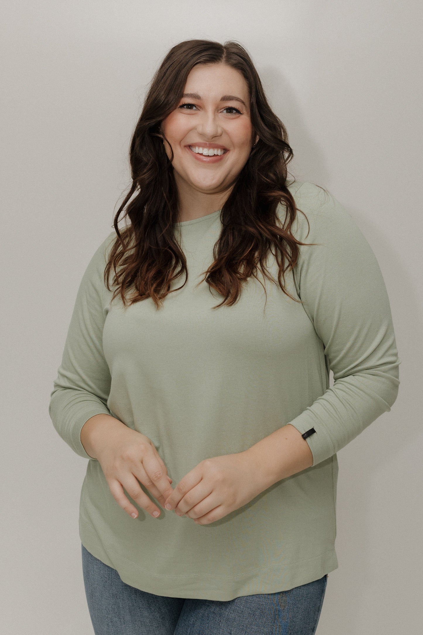 Woman wearing a light green long-sleeve top against a plain background
