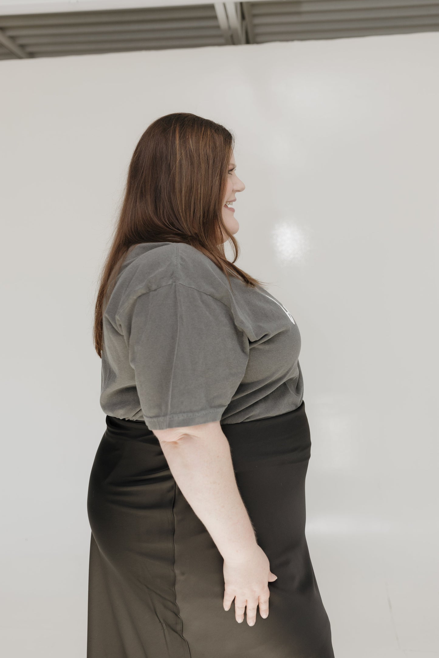 Person wearing a gray top and black skirt against a white background