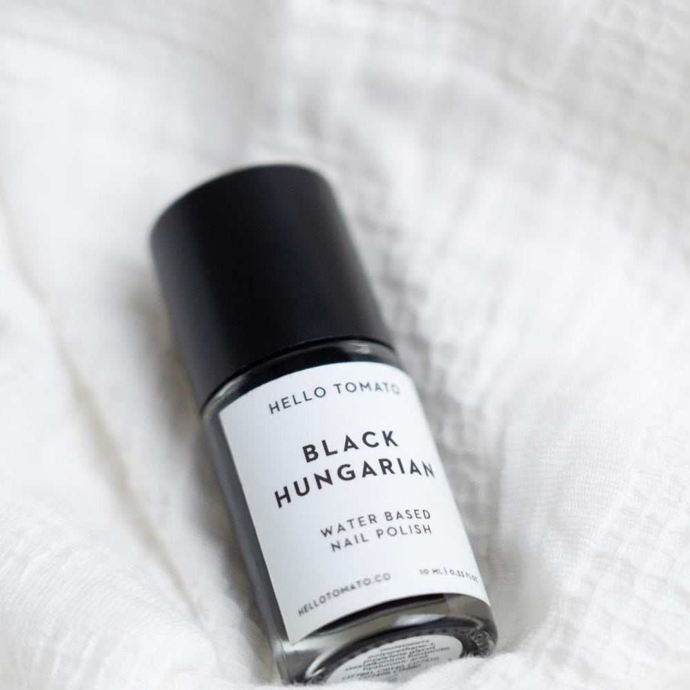 Black Hungarian water-based nail polish bottle on a white textured background