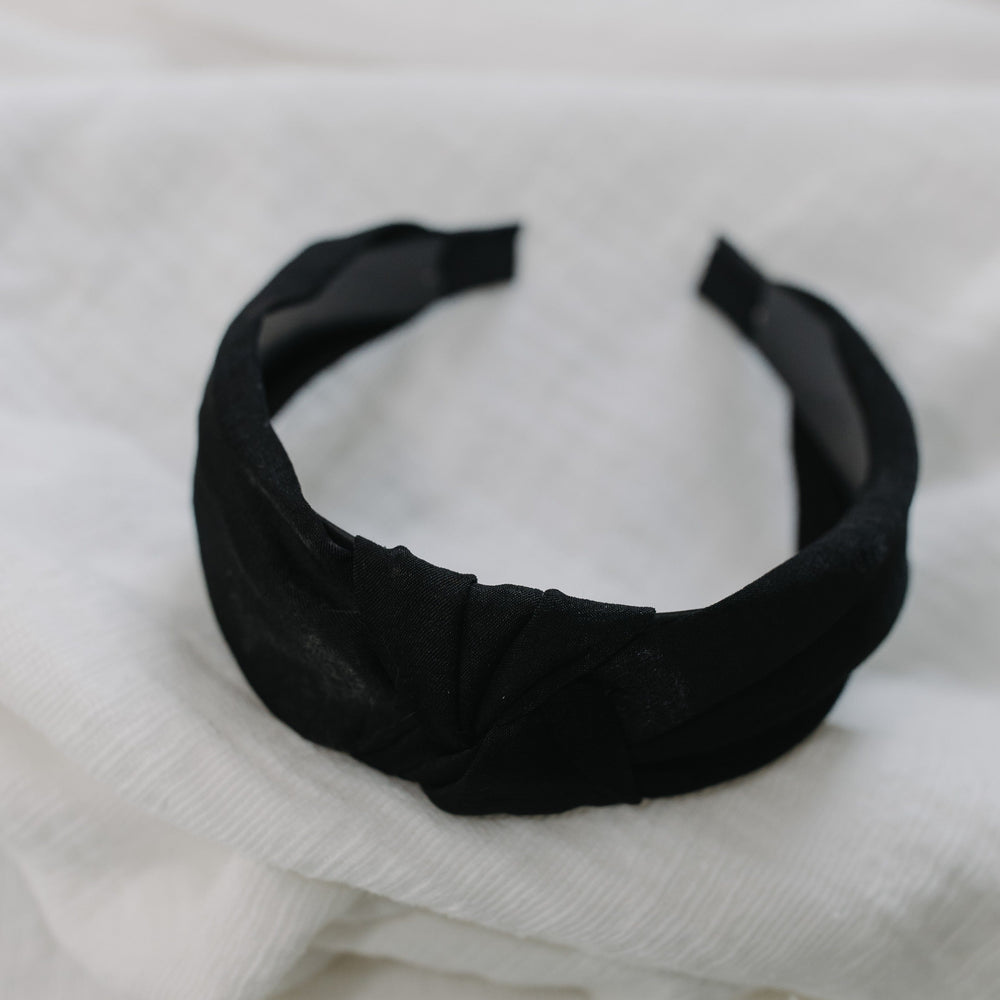 Black headband on a white textured fabric background
