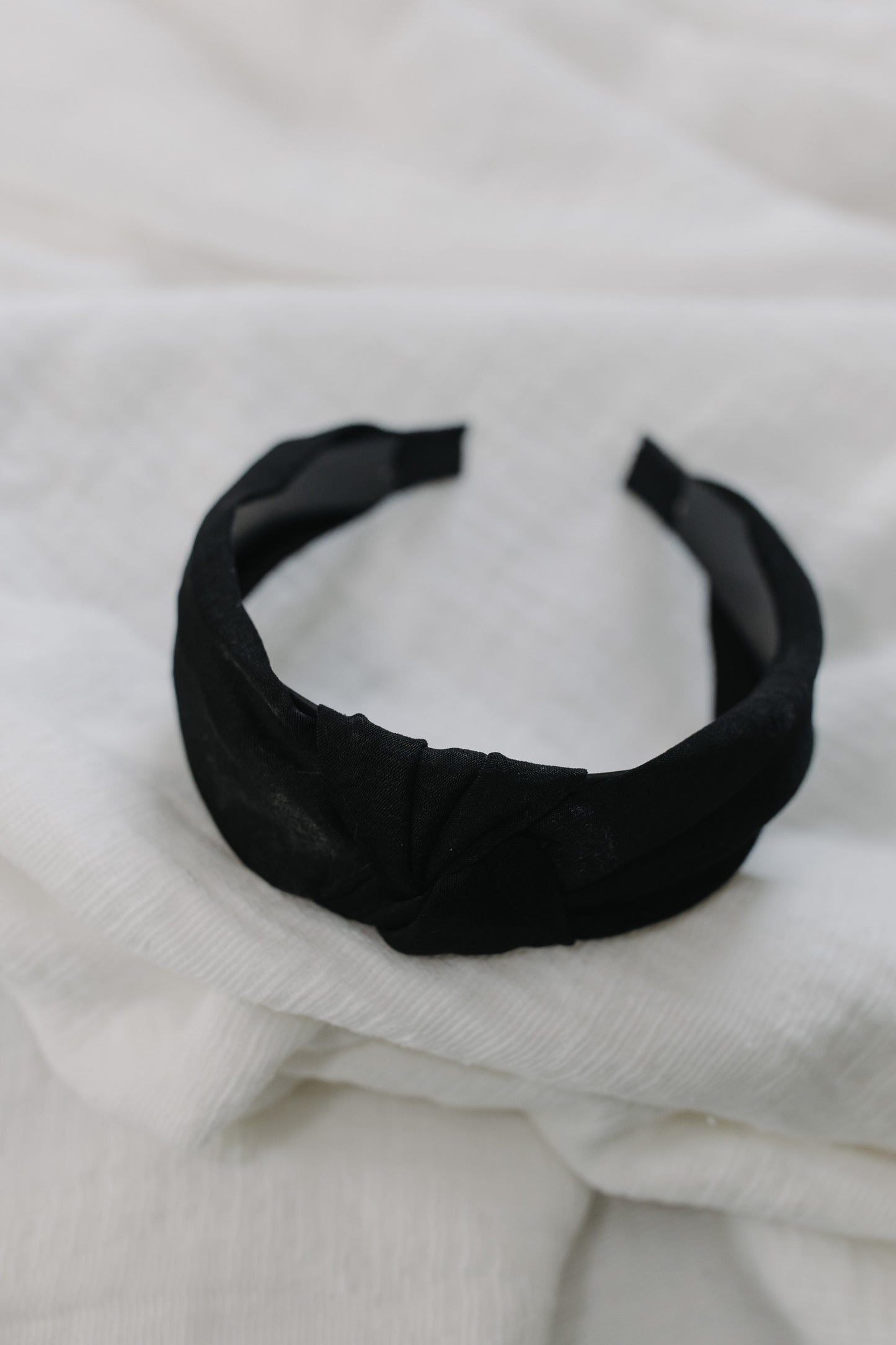 Black headband on a white textured fabric background