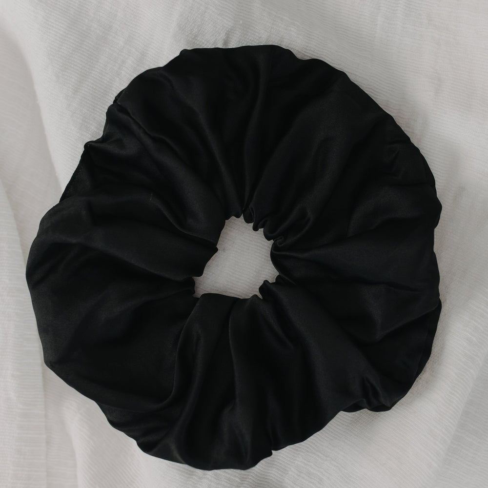 Black scrunchie on a white fabric background