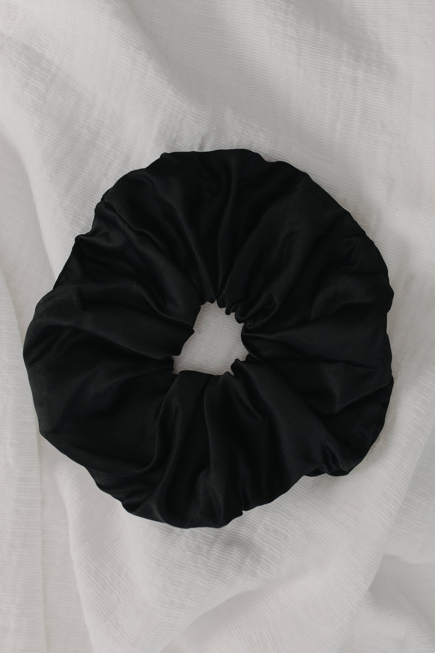 Black scrunchie on a white fabric background