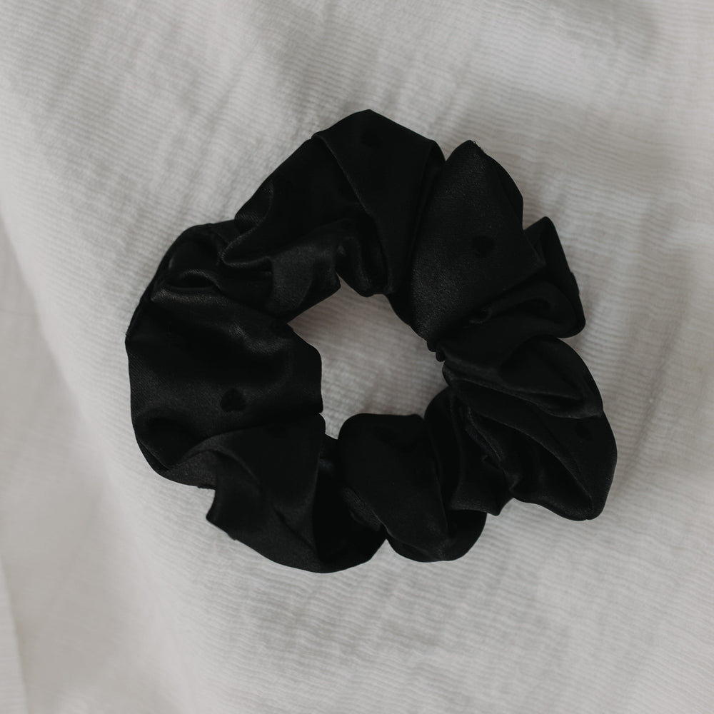 Black scrunchie on a white fabric background