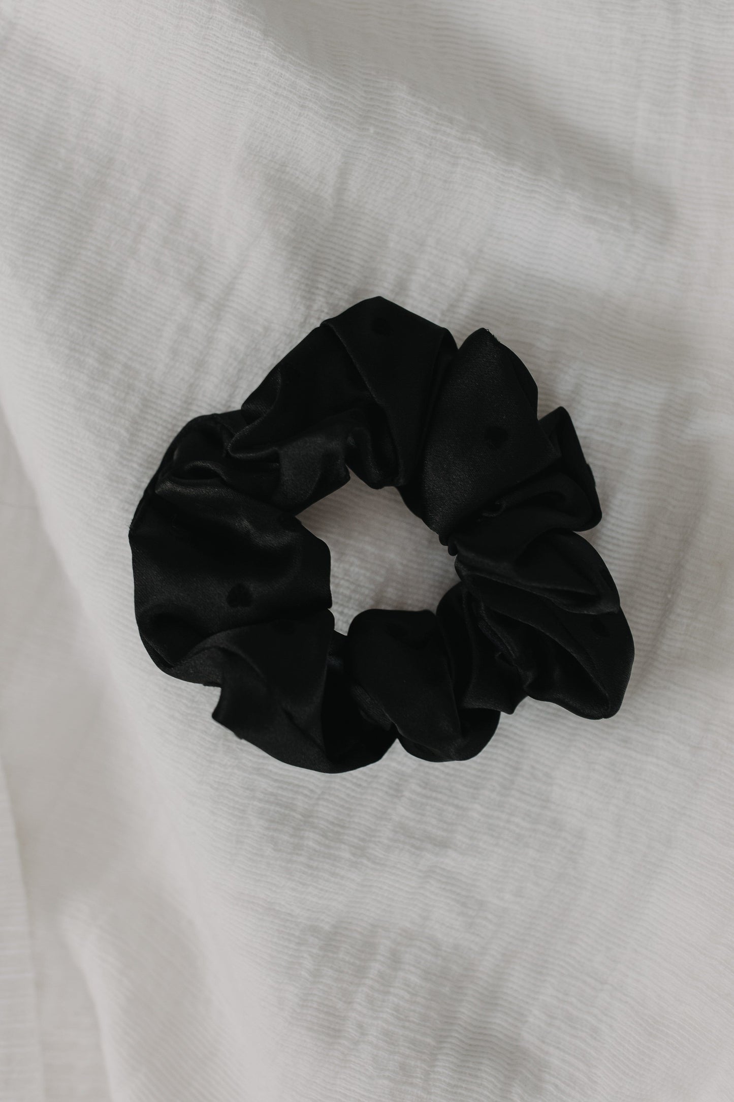Black scrunchie on a white fabric background
