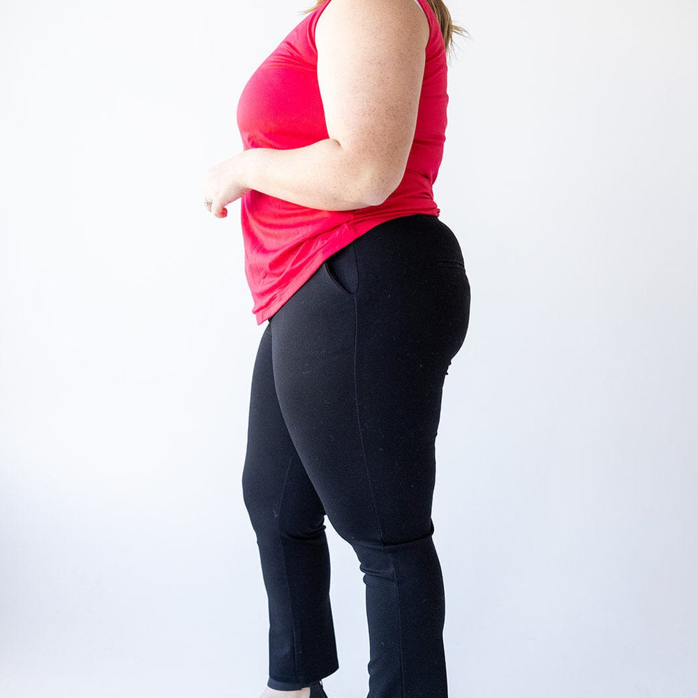 A person in a red sleeveless top and black dress pants stands sideways against a white background, showcasing the luxury fabric and wearing black sandals.