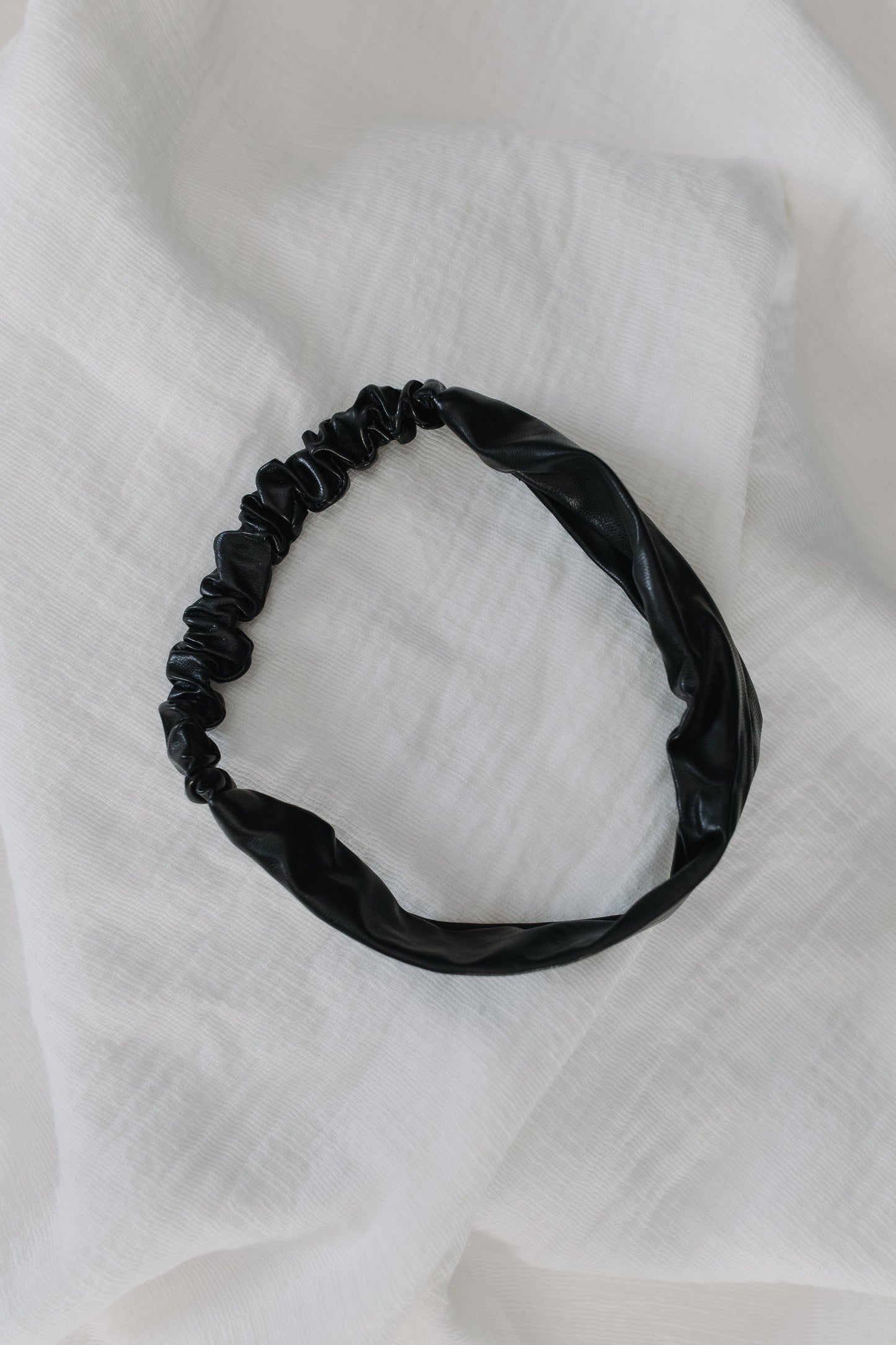 Black hairband on a white textured fabric background