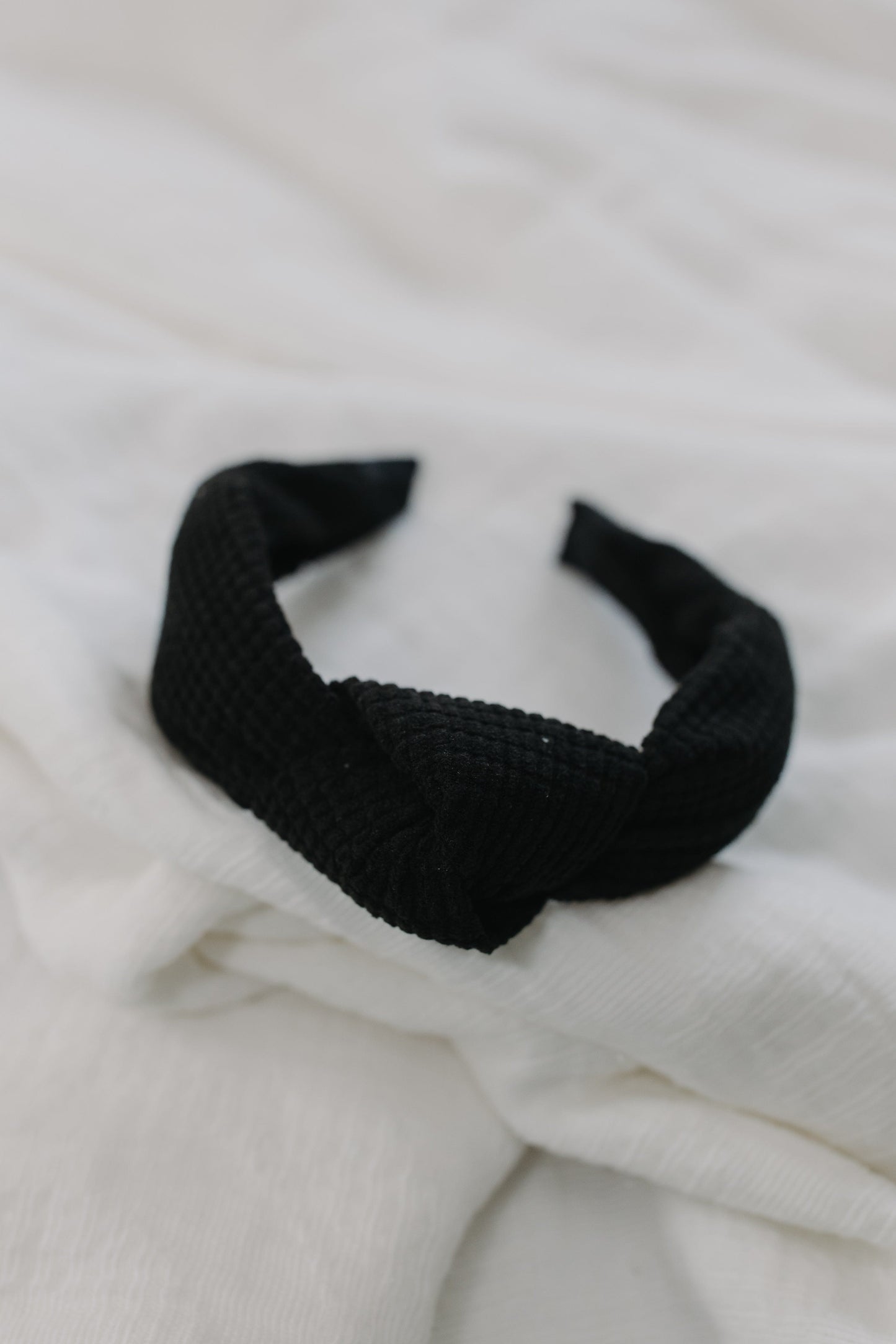 Black waffle texture headband against a white background