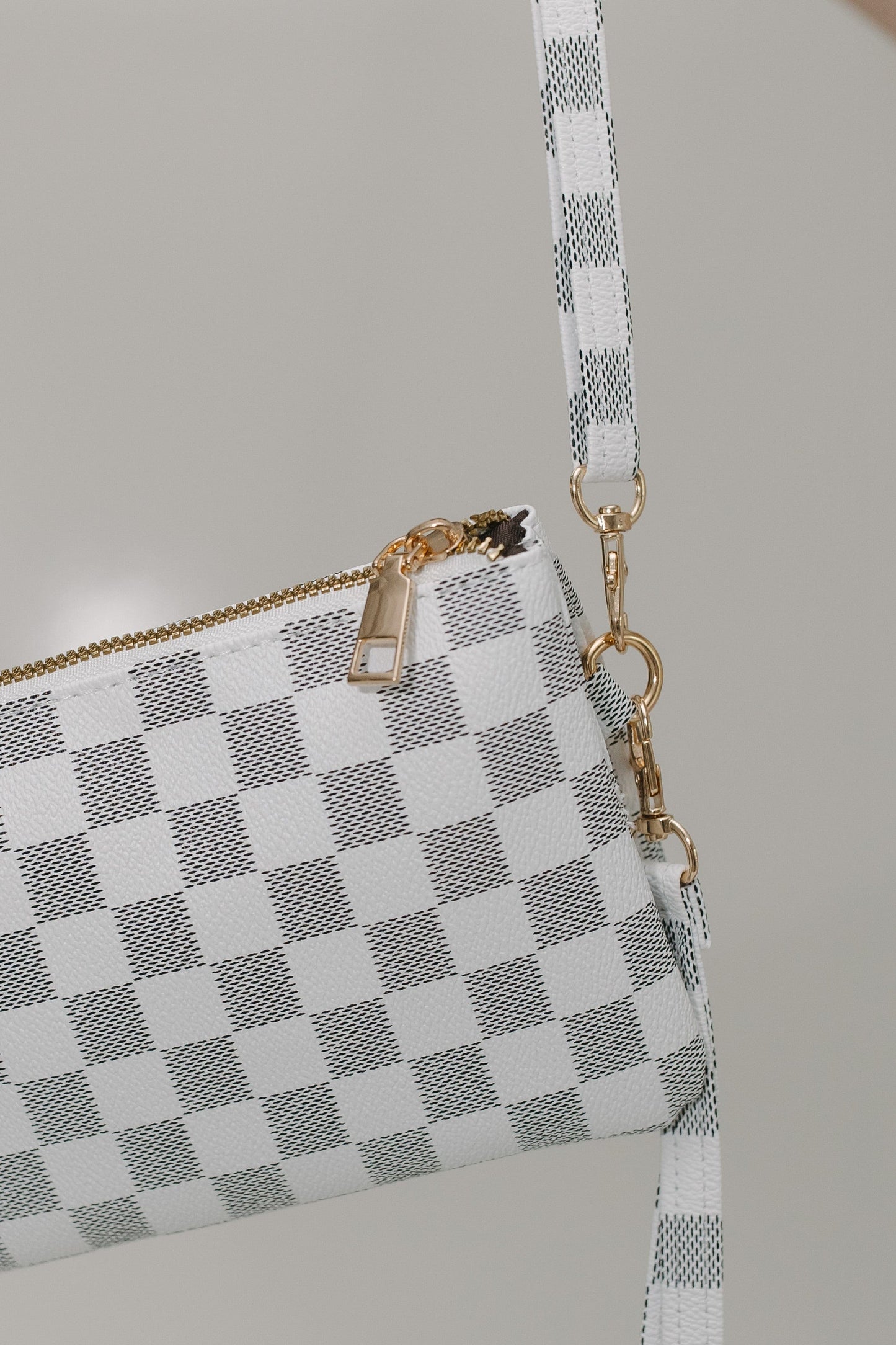 Checkered handbag with a strap on a neutral background