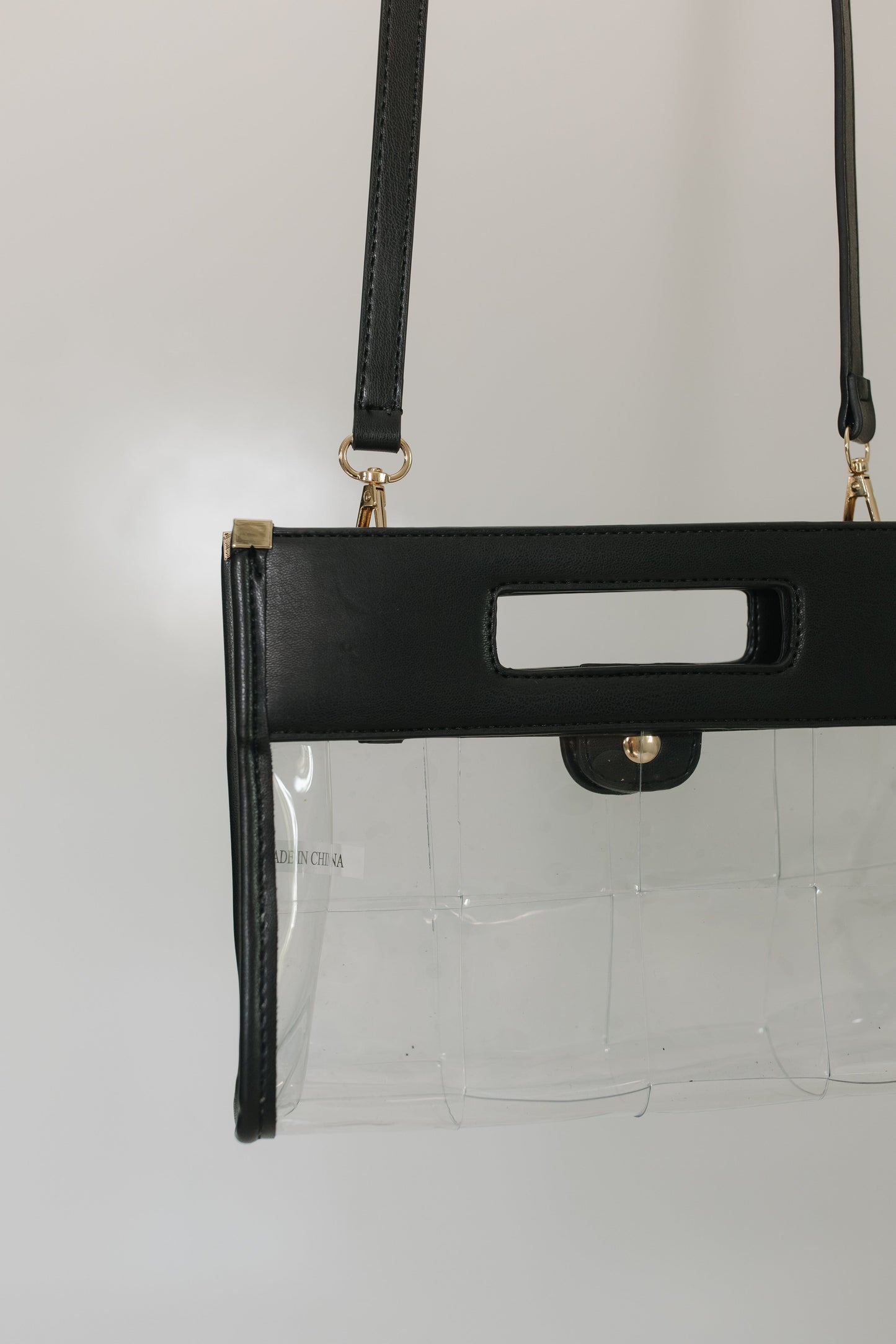 Black handbag with clear pouch on a light gray background