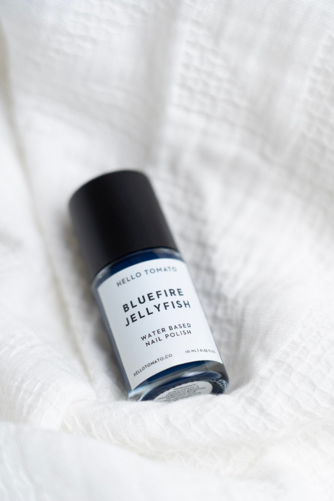 Bottle of Bluefire Jellyfish nail polish on a textured white surface