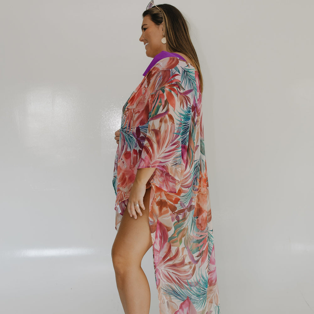 Woman wearing a colorful floral dress against a white wall