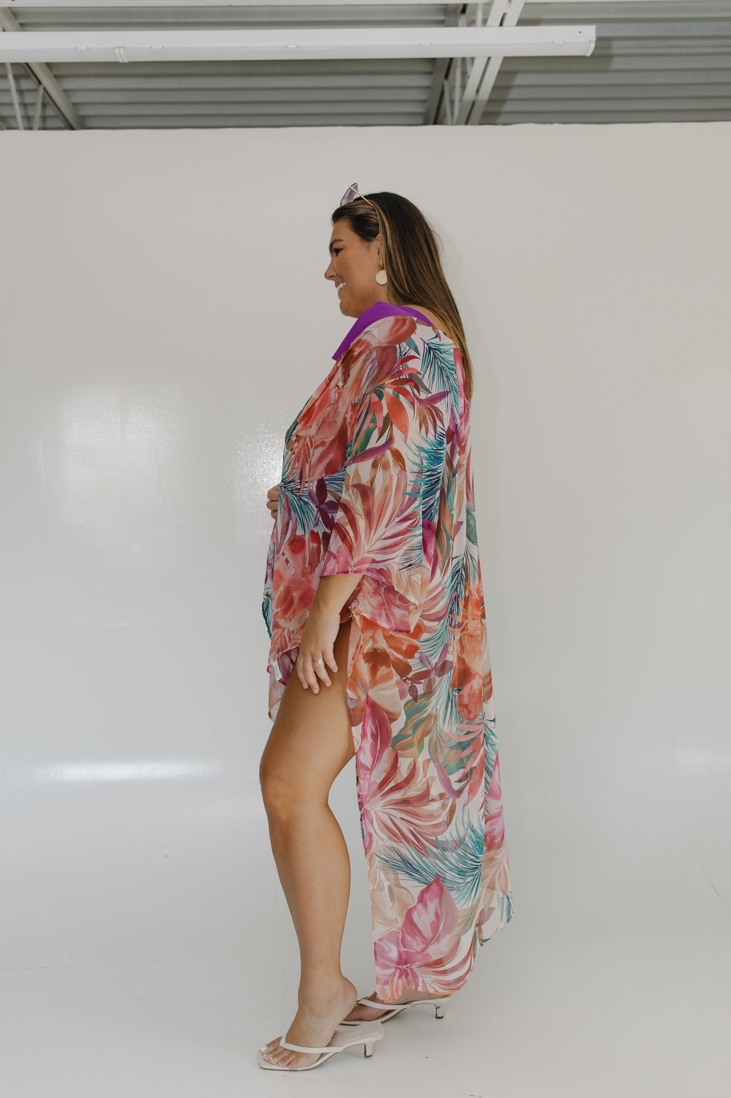 Woman wearing a colorful floral dress against a white wall