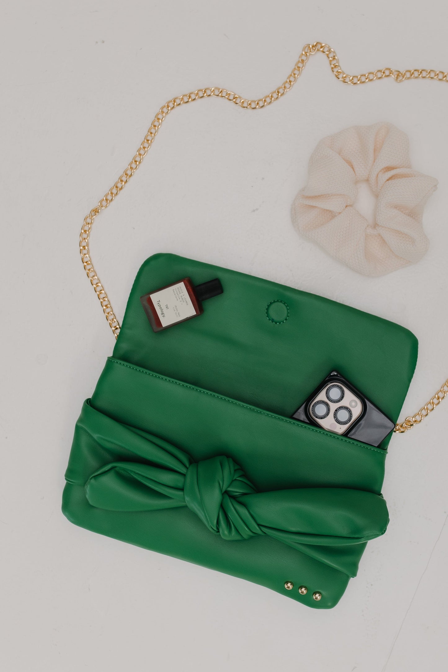 Green clutch bag with a knot detail on a light gray background