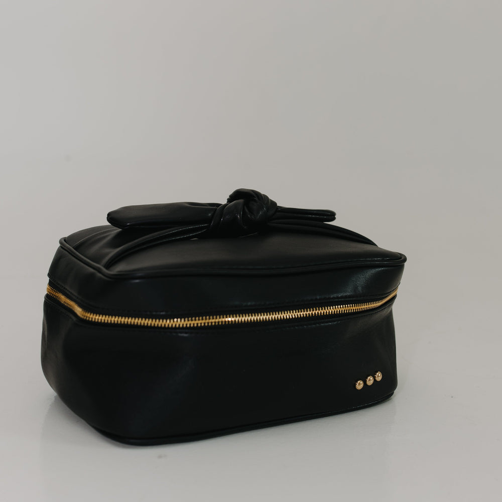 Black cosmetic bag with gold zipper on a light gray background