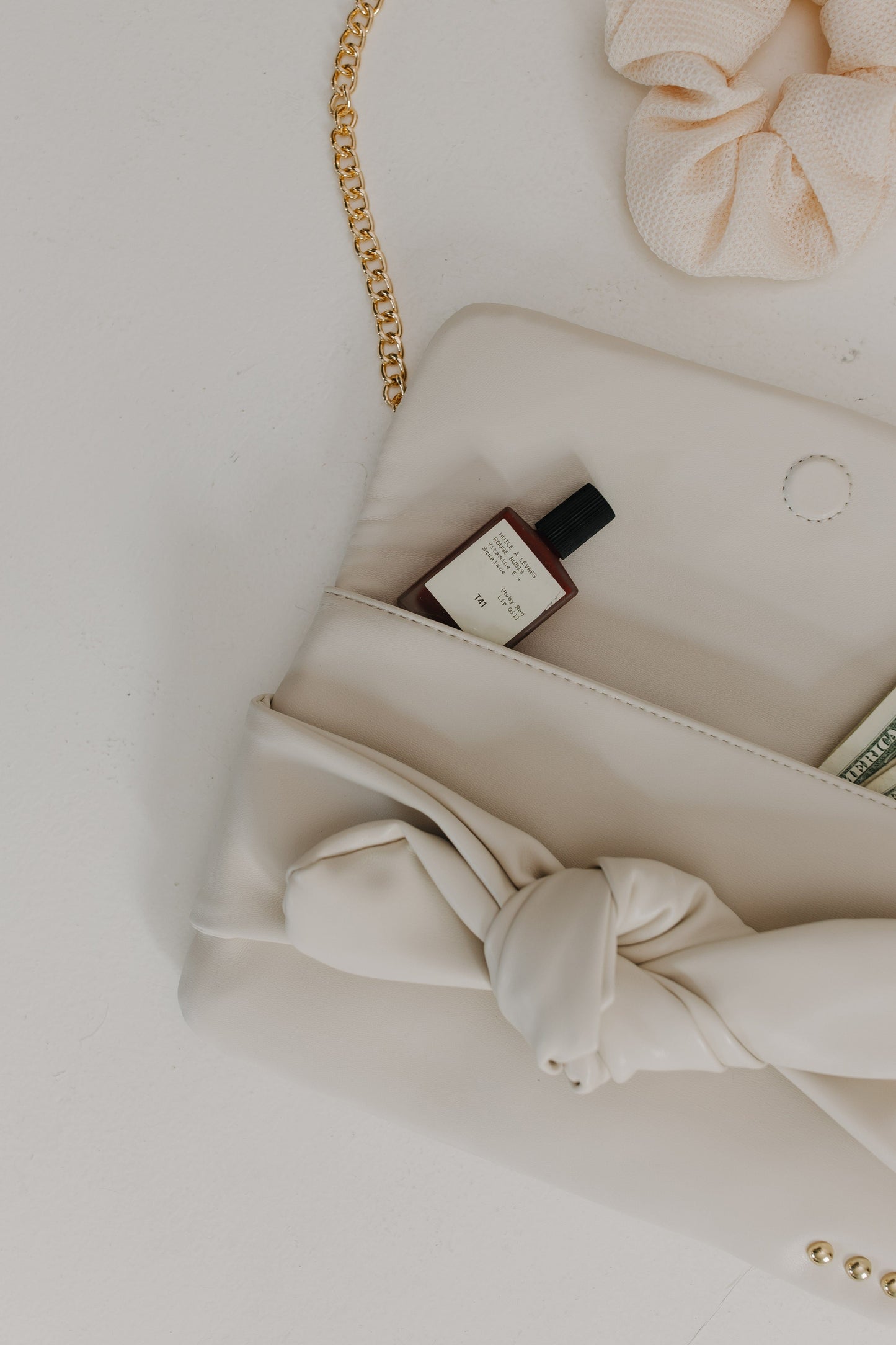 Beige handbag with a bow detail on a light background