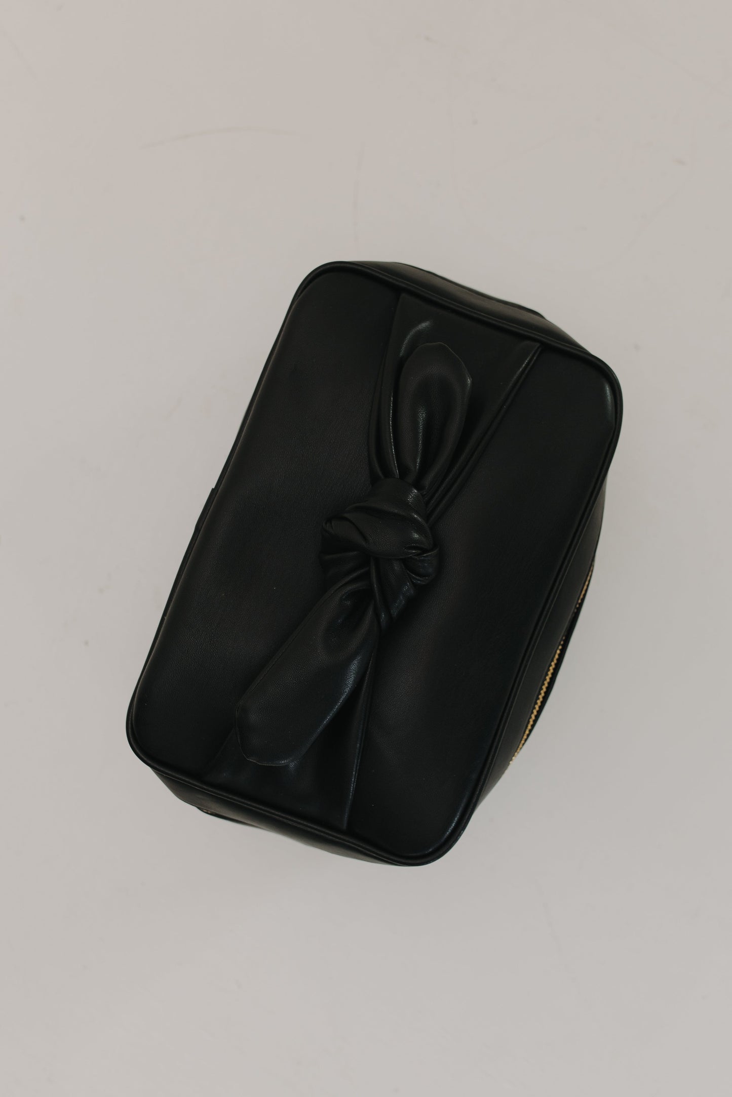 Black leather pouch with a knot on a light gray background