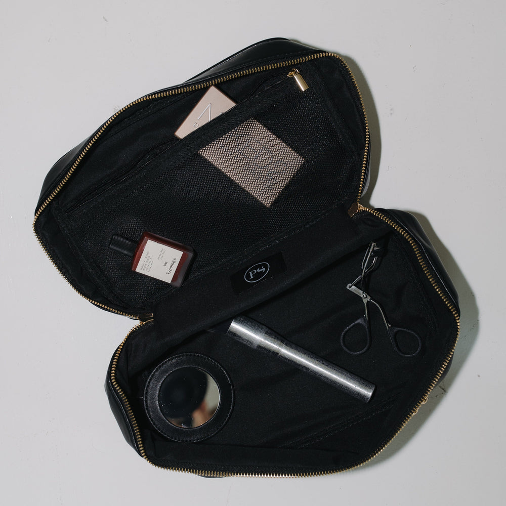 Black travel case with grooming items on a white background