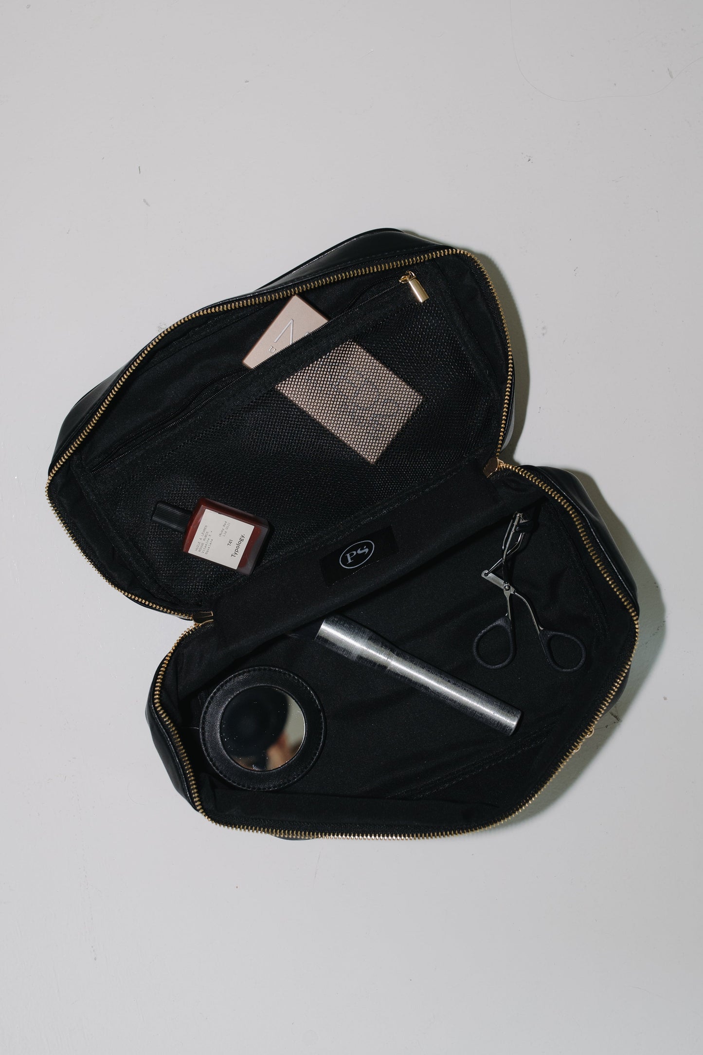 Black travel case with grooming items on a white background