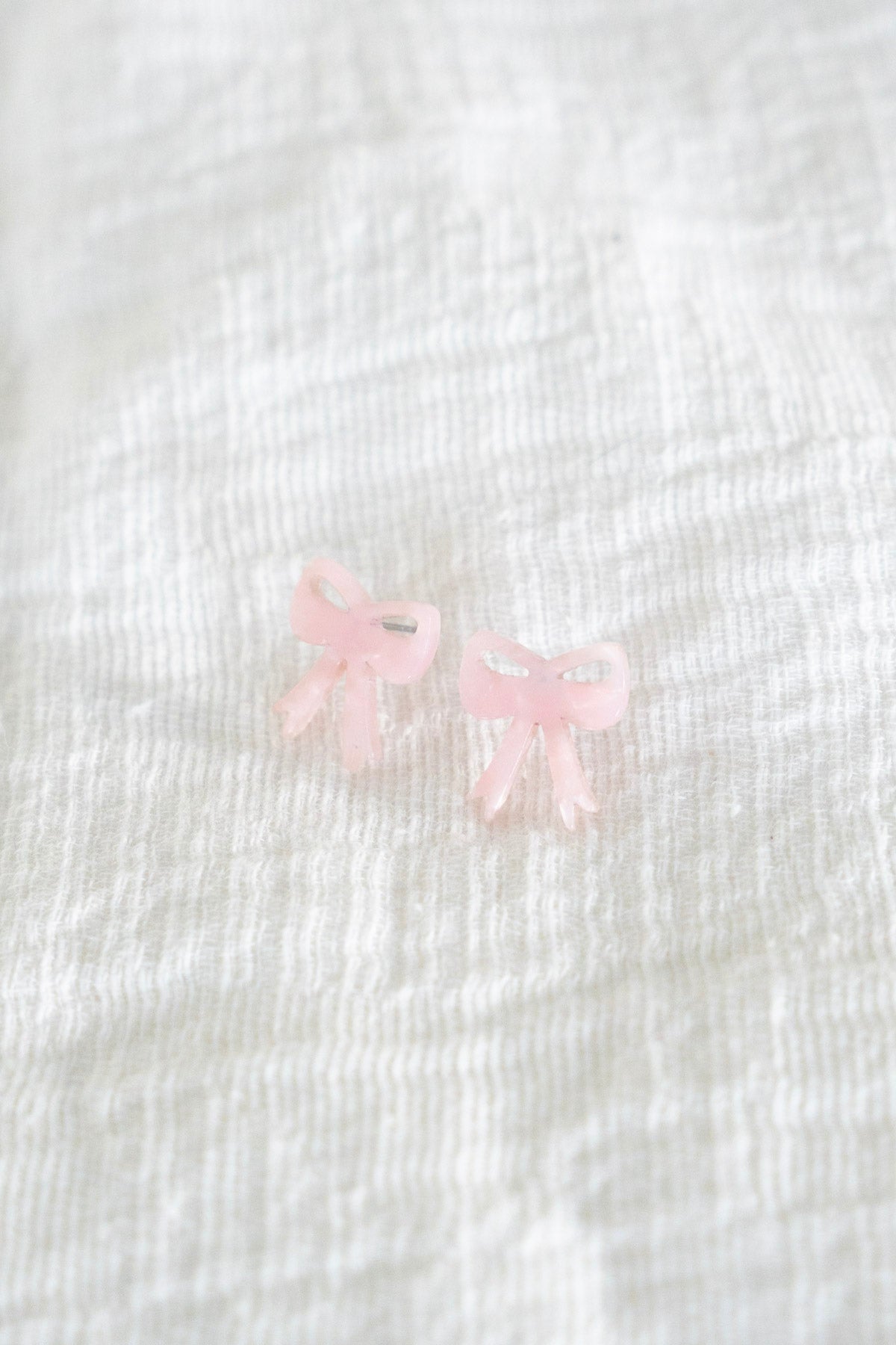 BOW STUDS IN BABY PINK 
 bow-shaped earrings are made with hypoallergenic stainless-steel posts and durable plant-based acrylic in pink.