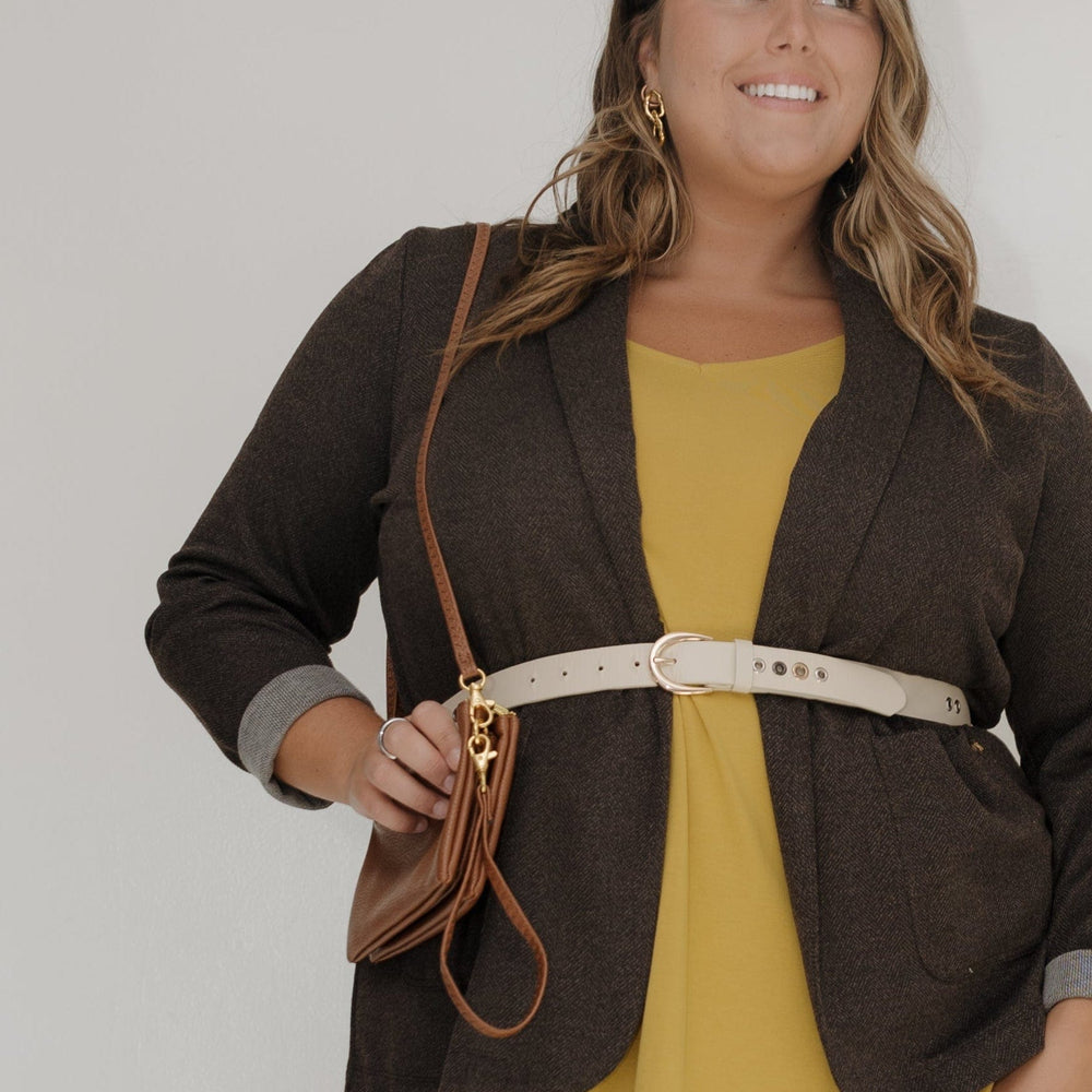 Woman wearing a yellow dress with a brown jacket against a white background