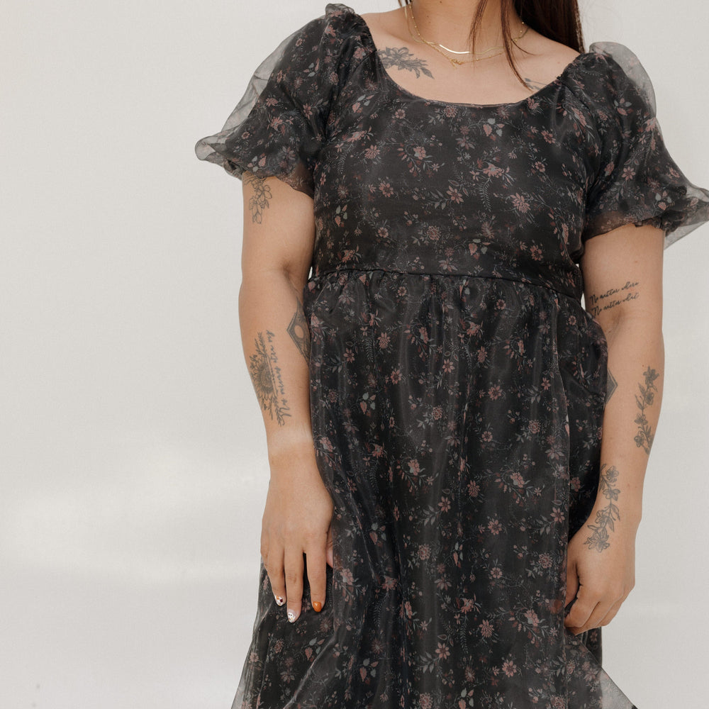 Woman wearing a black floral dress against a white background